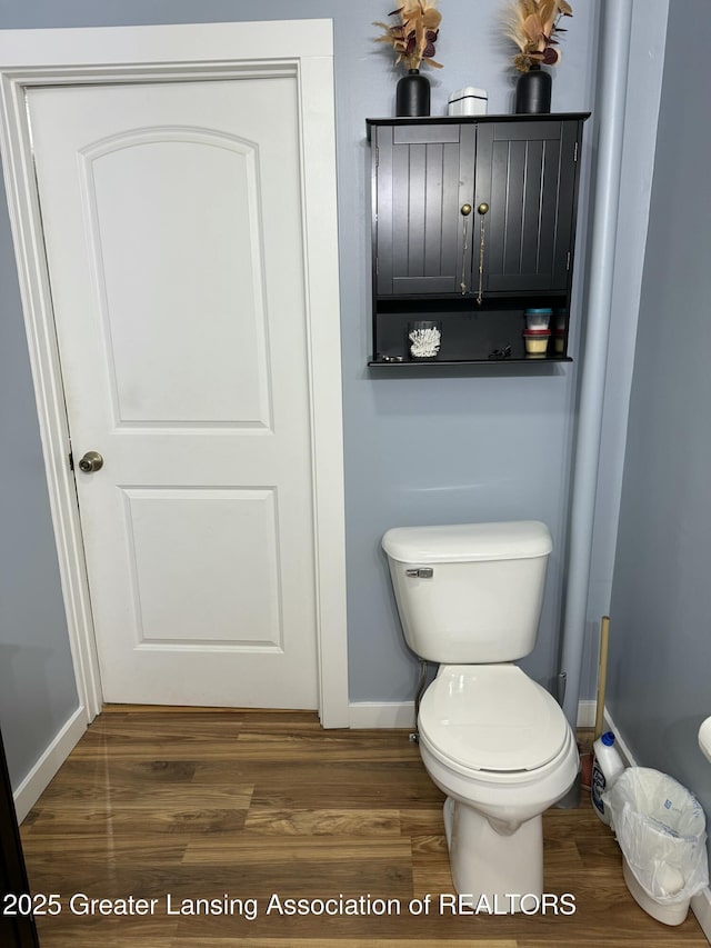 bathroom with toilet, wood finished floors, and baseboards