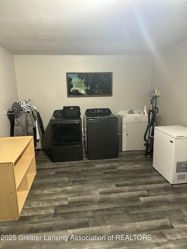 laundry area featuring washing machine and clothes dryer, dark wood-style floors, and a textured ceiling