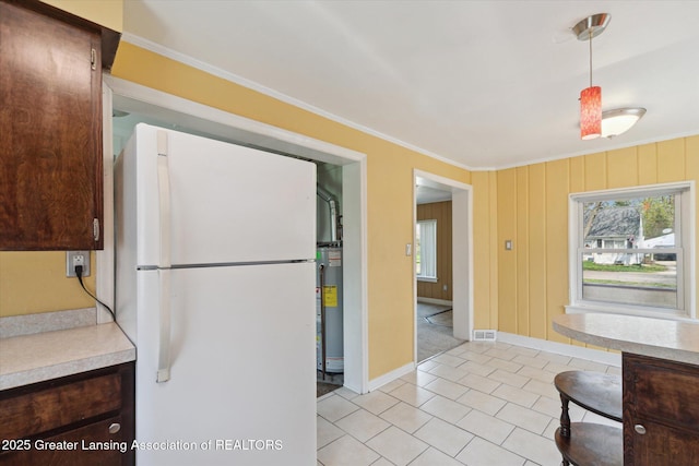 kitchen featuring ornamental molding, light tile patterned floors, freestanding refrigerator, and a healthy amount of sunlight