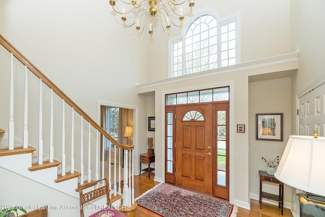 foyer featuring a high ceiling, a chandelier, wood finished floors, stairway, and baseboards
