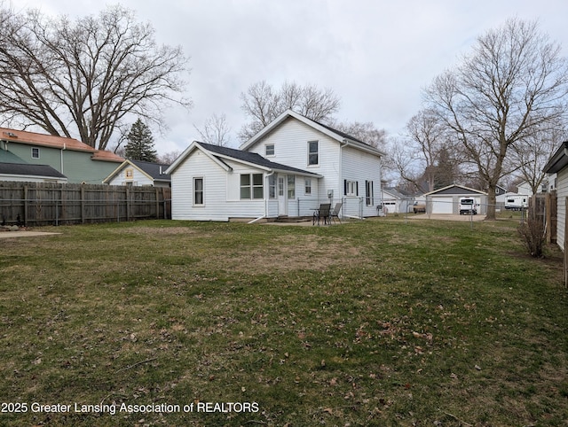 rear view of property with a yard, a detached garage, fence, and a patio area