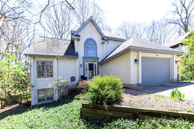 traditional home with a garage, concrete driveway, and roof with shingles