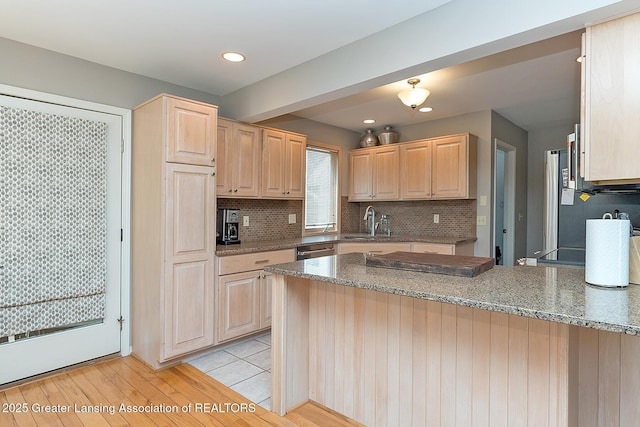 kitchen featuring recessed lighting, decorative backsplash, light brown cabinetry, a peninsula, and stone countertops