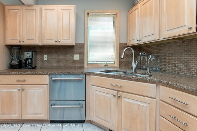 kitchen featuring light brown cabinetry, dark stone counters, backsplash, and a sink