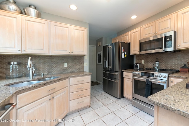 kitchen featuring decorative backsplash, light brown cabinetry, appliances with stainless steel finishes, a sink, and light tile patterned flooring