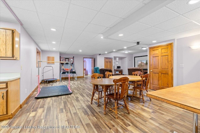 dining space with baseboards, recessed lighting, a paneled ceiling, and light wood-style floors