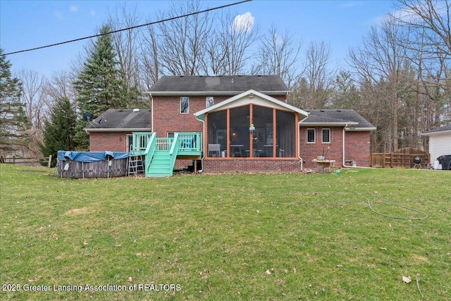 back of property featuring a sunroom, brick siding, and a yard