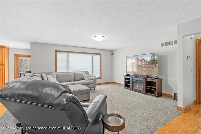 living area featuring baseboards, a textured ceiling, a wealth of natural light, and visible vents