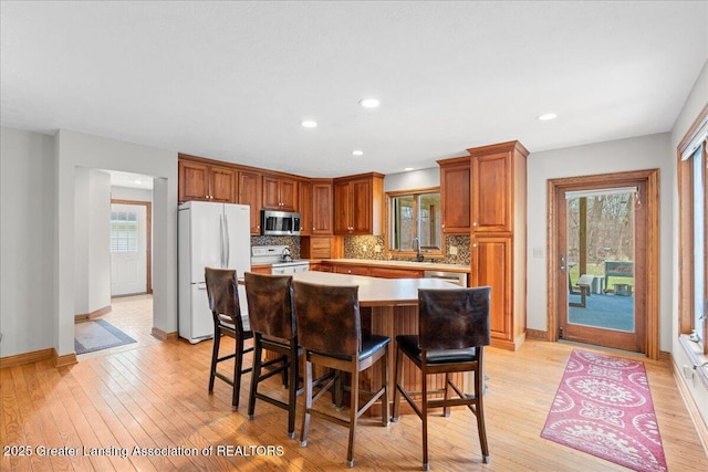 kitchen with tasteful backsplash, appliances with stainless steel finishes, a center island, and light wood-type flooring