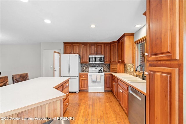 kitchen with light countertops, backsplash, a sink, light wood-style flooring, and stainless steel appliances