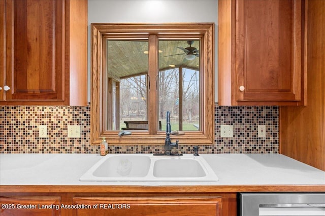 kitchen featuring backsplash, light countertops, a sink, and brown cabinetry