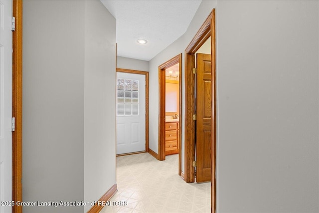 hall with baseboards and light floors