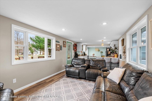 living area with baseboards, light wood finished floors, and recessed lighting