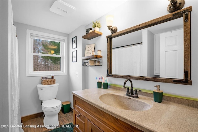 bathroom featuring toilet, wood finished floors, baseboards, and vanity