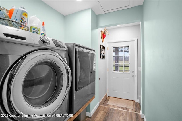 laundry area with washing machine and dryer, baseboards, laundry area, and wood finished floors