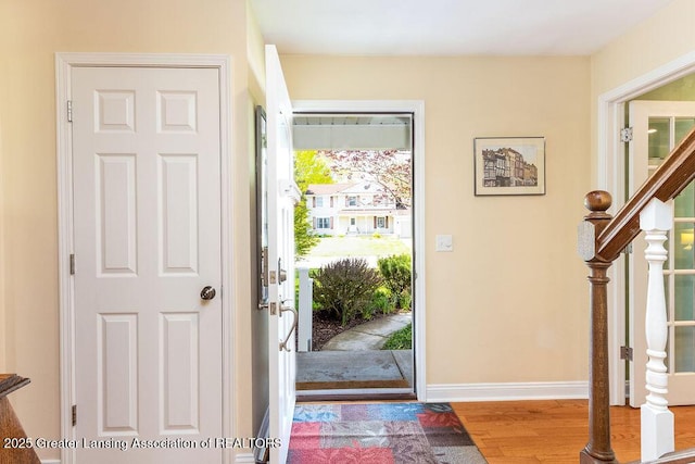 foyer entrance featuring wood finished floors, baseboards, and stairs
