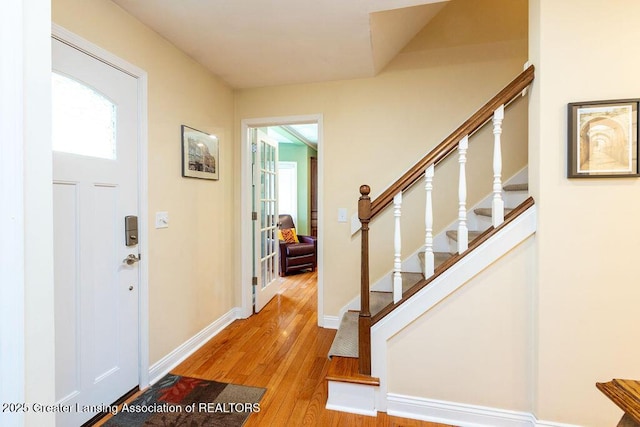 entryway featuring a wealth of natural light, wood finished floors, baseboards, and stairs