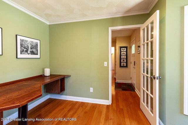 unfurnished office featuring wood finished floors, baseboards, and ornamental molding