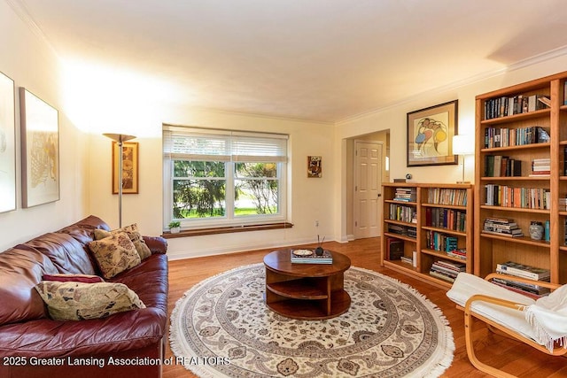 living area with baseboards, ornamental molding, and wood finished floors
