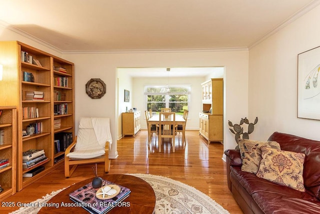 living room featuring light wood finished floors, baseboards, and ornamental molding
