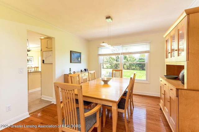 dining room featuring crown molding, light wood-style flooring, and baseboards