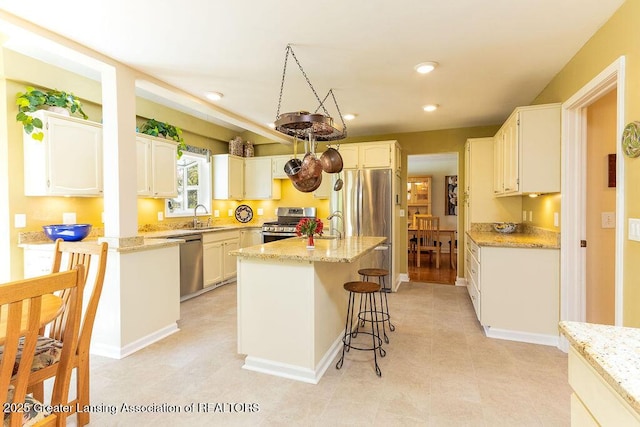 kitchen featuring a breakfast bar, a sink, light stone counters, and appliances with stainless steel finishes