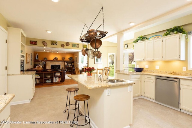 kitchen with a breakfast bar area, dishwasher, a sink, white cabinetry, and open floor plan