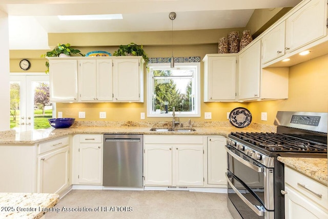 kitchen with a sink, a peninsula, stainless steel appliances, and a healthy amount of sunlight