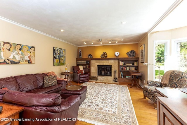 living area featuring a tile fireplace, crown molding, light wood-type flooring, and recessed lighting