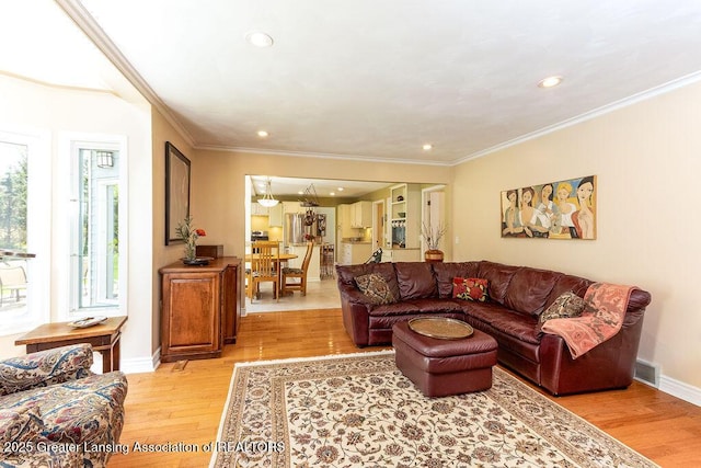 living area featuring light wood finished floors, crown molding, and recessed lighting