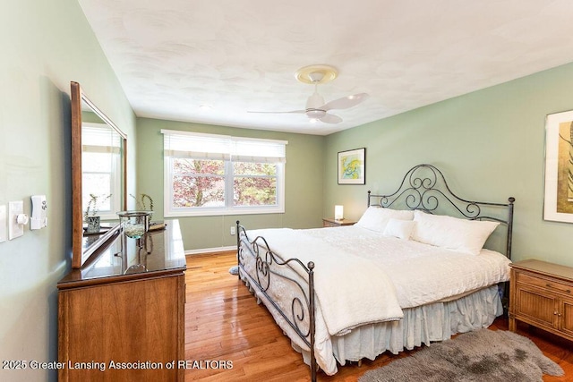 bedroom with a ceiling fan, baseboards, and wood finished floors