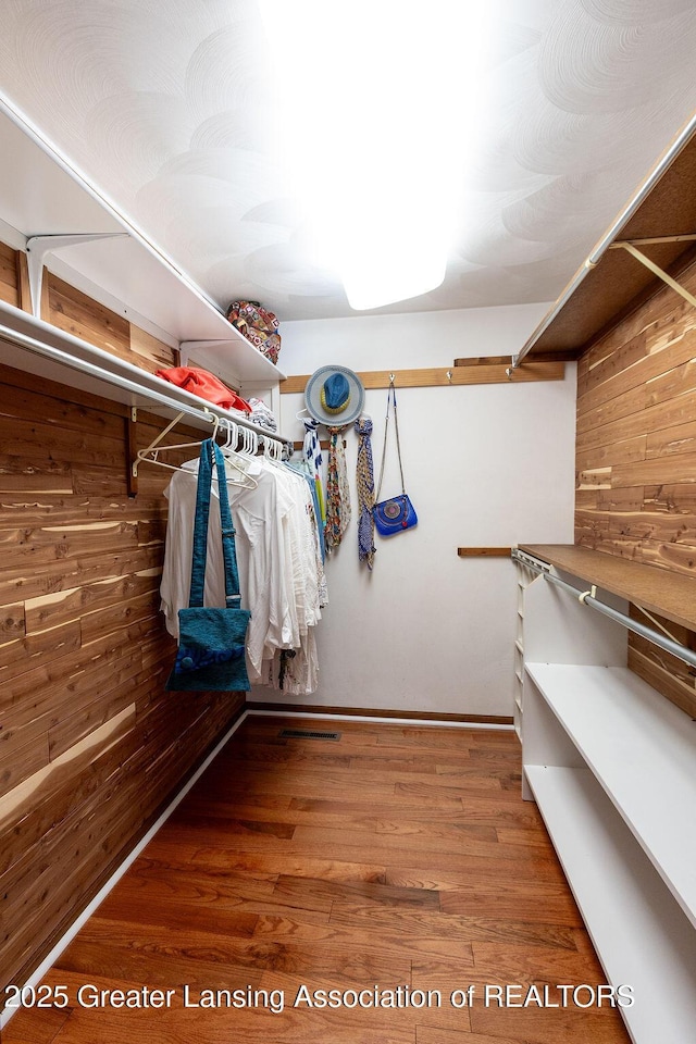 walk in closet with wood finished floors
