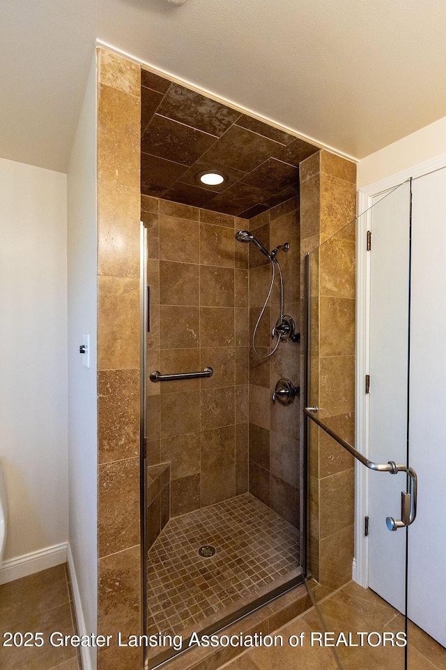 full bathroom with a stall shower, baseboards, and tile patterned floors