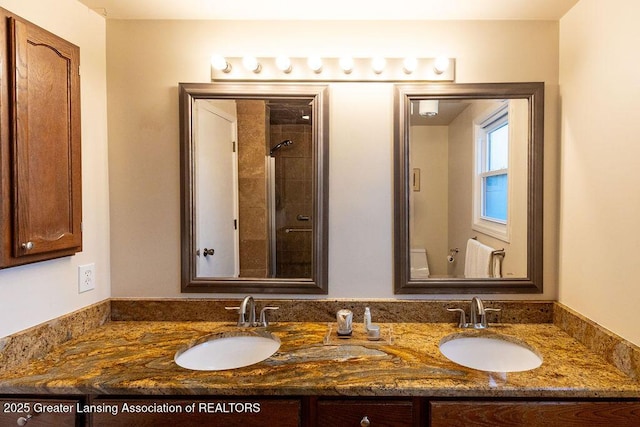 full bathroom featuring a sink, double vanity, and tiled shower