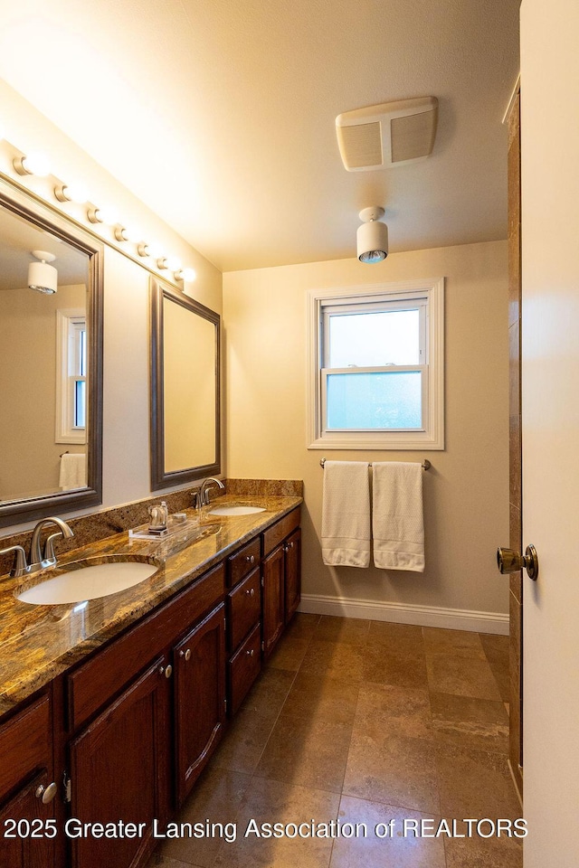 full bathroom with a sink, double vanity, baseboards, and visible vents