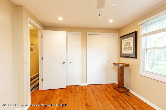 unfurnished bedroom featuring recessed lighting, two closets, visible vents, and light wood-style floors