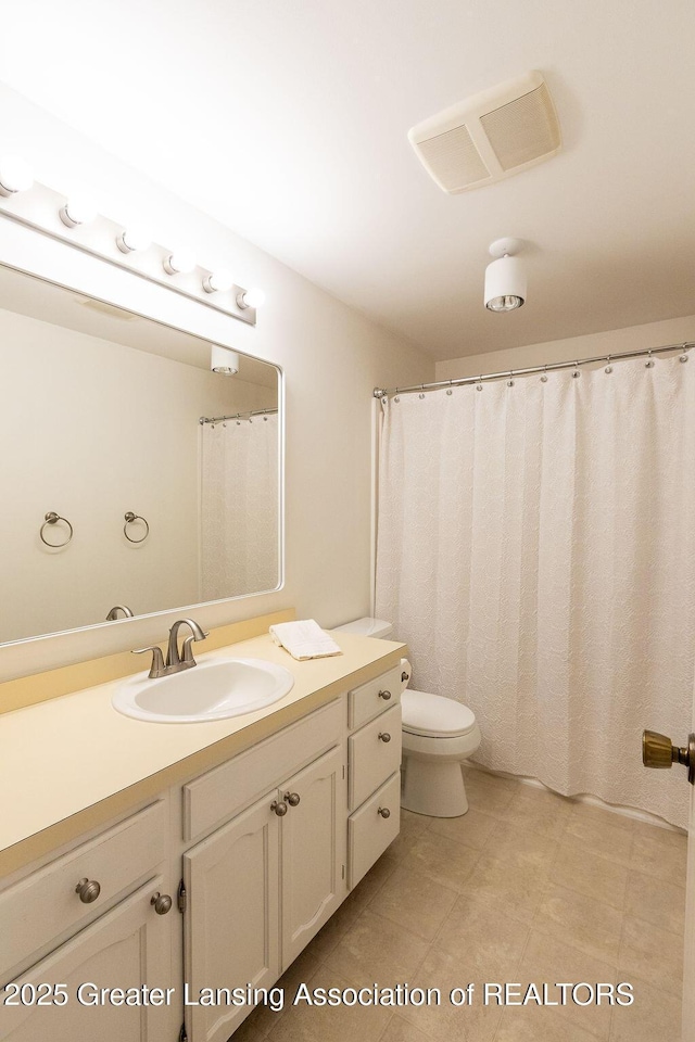 bathroom with toilet, vanity, and visible vents