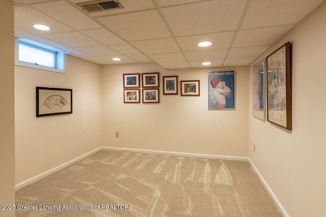 basement featuring baseboards, a drop ceiling, light carpet, and visible vents