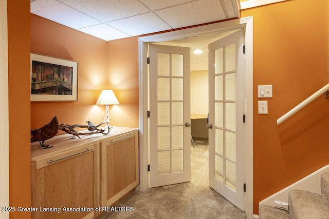 doorway with light carpet, stairs, and a drop ceiling