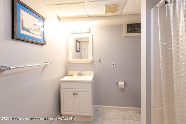 bathroom featuring a drop ceiling, visible vents, baseboards, tile patterned flooring, and vanity