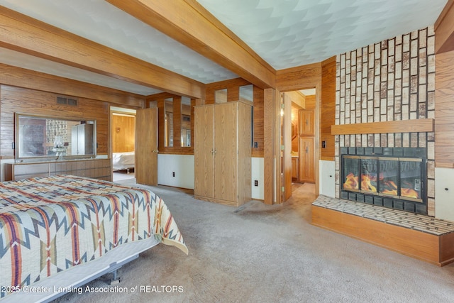 9605 Jason Rd, Laingsburg, MI 48848 - carpeted bedroom with beamed ceiling, a glass covered fireplace, visible vents, and wood walls