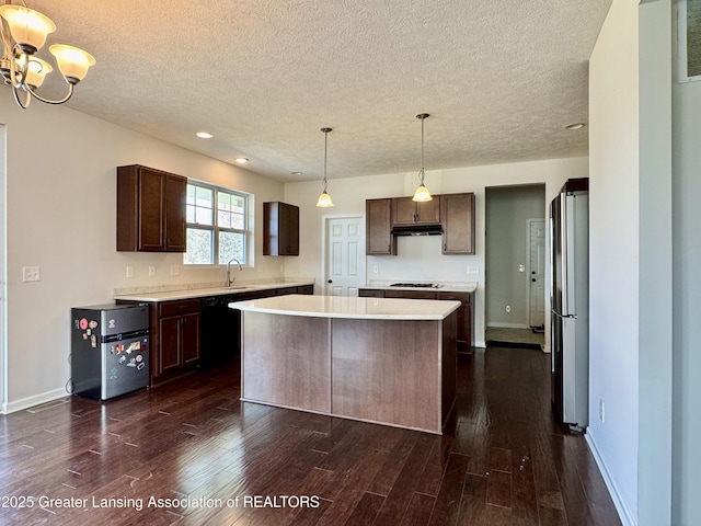 2632 Carnoustie Dr, Okemos, MI 48864 - kitchen with a textured ceiling, freestanding refrigerator, gas cooktop, under cabinet range hood, and dark wood finished floors