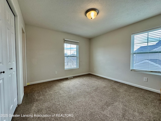 2632 Carnoustie Dr, Okemos, MI 48864 - unfurnished bedroom featuring visible vents, a closet, baseboards, a textured ceiling, and carpet floors