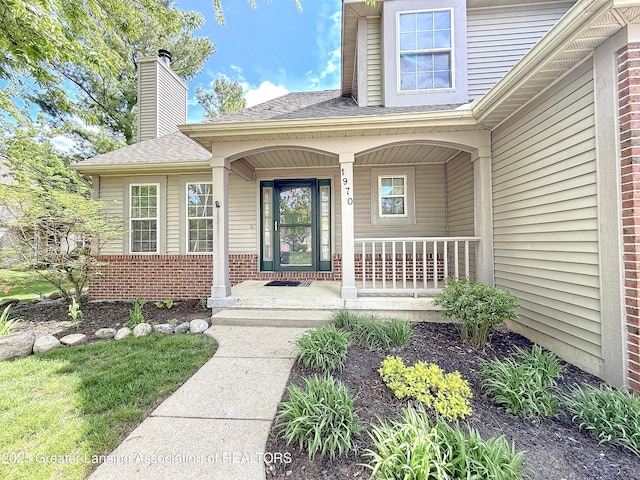 1970 Hollowbrook Dr, Holt, MI 48842 - entrance to property featuring covered porch, brick siding, a shingled roof, and a chimney
