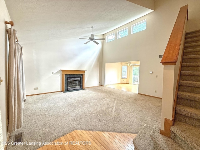 1970 Hollowbrook Dr, Holt, MI 48842 - unfurnished living room with a ceiling fan, a textured ceiling, a fireplace, carpet, and stairs