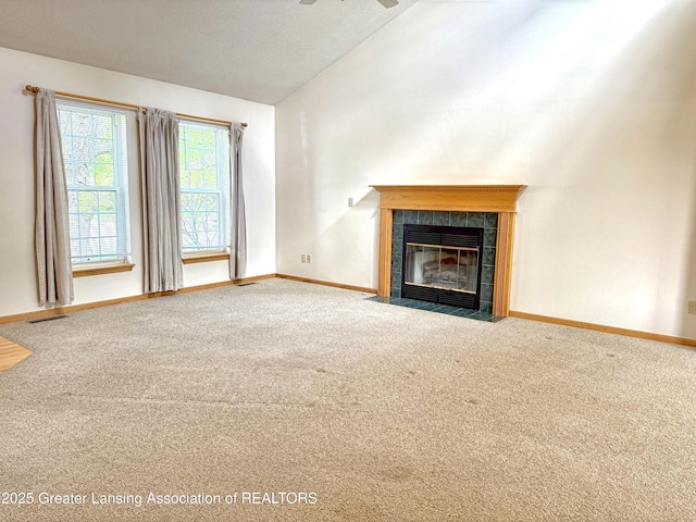 1970 Hollowbrook Dr, Holt, MI 48842 - unfurnished living room featuring visible vents, a tiled fireplace, vaulted ceiling, baseboards, and carpet