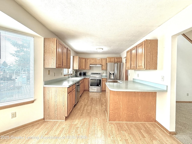 1970 Hollowbrook Dr, Holt, MI 48842 - kitchen featuring light wood-type flooring, light countertops, a textured ceiling, a sink, and stainless steel appliances