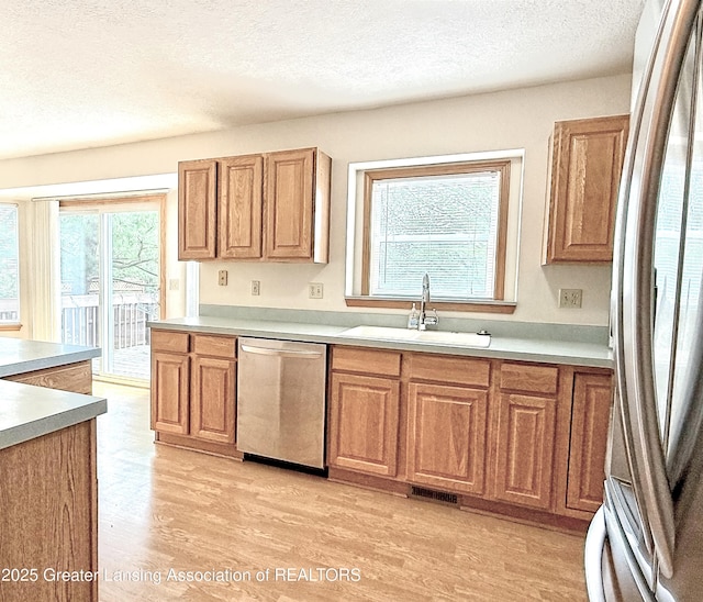 1970 Hollowbrook Dr, Holt, MI 48842 - kitchen with a sink, a textured ceiling, stainless steel appliances, light wood-type flooring, and visible vents