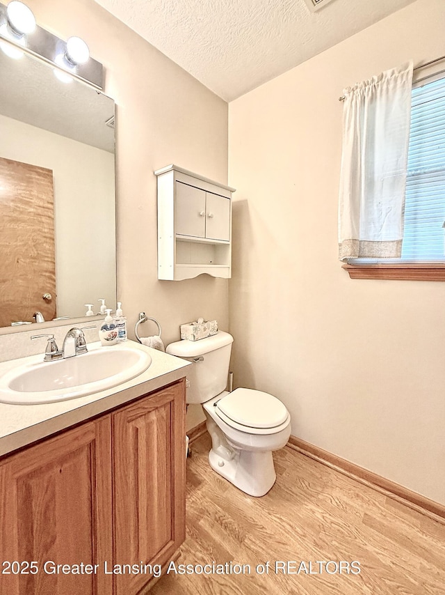1970 Hollowbrook Dr, Holt, MI 48842 - half bath with vanity, a textured ceiling, toilet, and wood finished floors