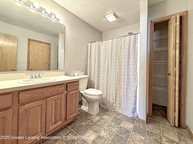 1970 Hollowbrook Dr, Holt, MI 48842 - bathroom with vanity, a walk in closet, stone finish floor, and toilet